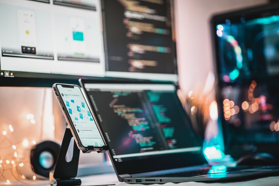 Vista de cerca de un setup tecnológico con gadgets, pantalla de código y smartphone
