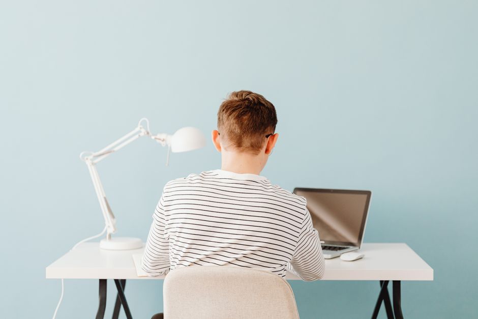 Adolescente usando laptop en un entorno minimalista con fondo azul