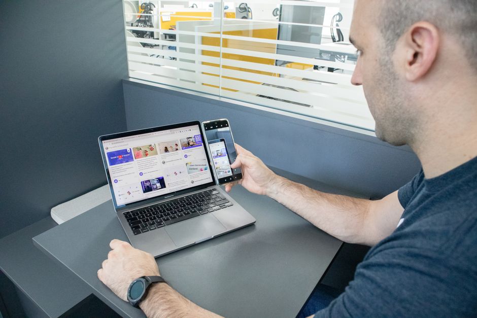Hombre multitareando con laptop y smartphone en una oficina contemporánea